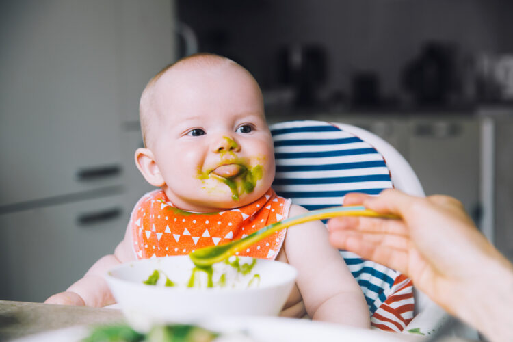 cute baby eating green solid foods