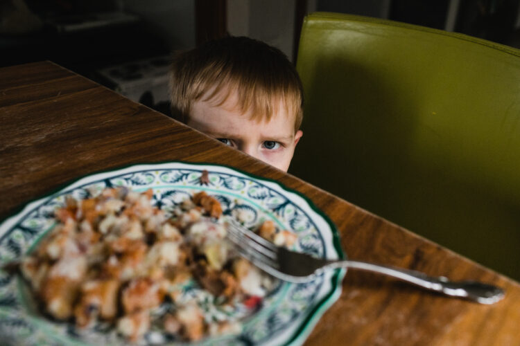 image of a grumpy toddler child refusing to eat plate of food for dinner